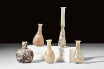 COLLECTION OF FIVE ROMAN GLASS BOTTLES

 Ca. AD 100-300
 A group of five glass flasks used to store perfumed oil, or unguentum. The vessels in this...