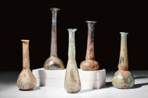 COLLECTION OF FIVE LARGE ROMAN GLASS BOTTLES

 Ca. AD 100-300 
 A group of five glass bottles, each with a globular lower body and a long tubular n...