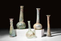 COLLECTION OF FIVE LARGE ROMAN GLASS BOTTLES

 Ca. AD 100-300 
 A group of five glass bottles, each with its unique shape. These flasks were used t...