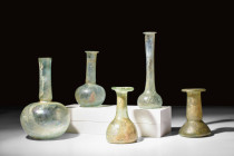 COLLECTION OF FIVELARGE ROMAN GLASS BOTTLES

 Ca. AD 100-300 
 A group of five glass bottles. Two of these bottles exhibit a bulbous lower body, wh...