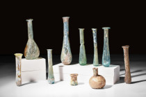 COLLECTION OF 10 ROMAN GLASS BOTTLES

 Ca. AD 100-300 
 A group of 10 assorted glass bottles, incorporating piriform and cylindrical unguentaria, a...