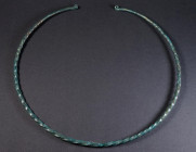A LARGE EUROPEAN LATE BRONZE AGE TWISTED TORQUE Circa 10th-8th century BC. Large, twisted hoop of solid bronze, the plain tapering ends with flattened...