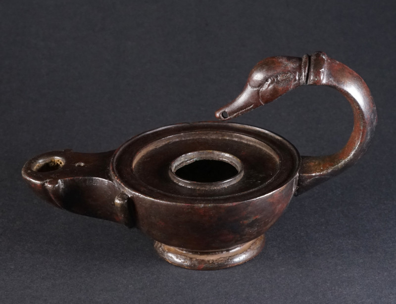 A ROMAN BRONZE OIL LAMP WITH A SWAN HEAD HANDLE Circa 1st-2nd century AD. The ro...