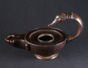 A ROMAN BRONZE OIL LAMP WITH A SWAN HEAD HANDLE Circa 1st-2nd century AD. The round body with raised, profiled edge set on a low foot ring; with a cir...