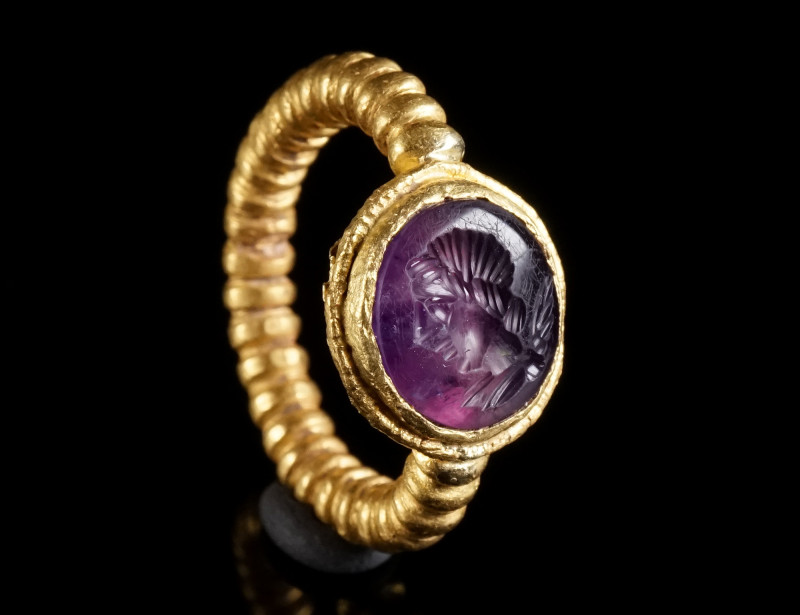 A LATE ROMAN GOLD RING WITH AN AMETHYST INTAGLIO Circa 4th century AD. Composed ...