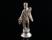 A ROMAN BRONZE STATUETTE OF MERCURY Circa 2nd-3rd century AD. A stylised representation of Mercury on a profiled round base; the god is wearing a wing...