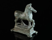 A ROMAN BRONZE STATUETTE OF A STRIDING HORSE Circa 2nd-3rd century AD. The right foreleg raised, the head slightly turned to the left; some incised an...