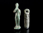 TWO ROMAN BRONZE FIGURAL AMULET PENDANTS Circa 2nd-3rd century AD. One probably depicting Harpocrates (?), holding his right hand to his mouth and his...