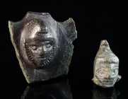 TWO ROMAN BRONZE APPLIQUES WITH A HEAD OF ATTIS Circa 2nd-3rd century AD. Both showing Attis with Phrygian cap. One probably originally a pelta-shaped...