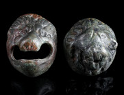 TWO ROMAN BRONZE LION HEAD APPLIQUES Circa 2nd-3rd century AD. One with wide open mouth and a bronze pin for attachment at the back; the other more de...