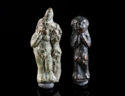 TWO ROMAN BRONZE FIGURAL AMULET PENDANTS Circa 2nd-3rd century AD. One depicting Harpocrates with his finger to his mouth, wearing the crowns of Upper...