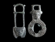 TWO BYZANTINE BRONZE CLOAK CLASPS WITH HEADS Circa 6th-8th century AD. One part each of a two-part toggle fastening. Both with a stylised face, the ci...