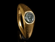 A HEAVY ROMAN GOLD RING WITH A GREEN CHALCEDONY INTAGLIO Circa 3rd century AD. Ring with wide gold hoop and large, angled, and facetted shoulders; the...