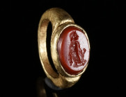 A ROMAN GOLD RING WITH A CARNELIAN INTAGLIO Circa 2nd-3rd century AD. Ring with an offset oval bezel set with a carnelian intaglio depicting Asclepius...