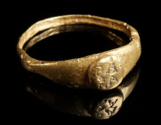 A ROMAN GOLD RING WITH INSCRIPTION Circa 2nd-3rd century AD. With an offset circular bezel and flared shoulders; the bezel with an abbreviated inscrip...