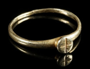 A LATE ANTIQUE GOLD RING WITH A CROSS Circa 4th-6th century AD. Ring with small, projecting round bezel decorated with a cross. Slightly bent. Ring si...