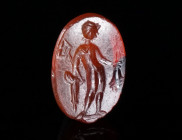 A ROMAN CARNELIAN INTAGLIO WITH MERCURY Circa 2nd-3rd century AD. Small oval intaglio depicting Mercury standing right, holding a stylised herald's st...