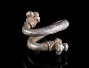 A GREEK SILVER HAIR SPIRAL Circa 5th-4th century BC. Hair spiral formed from thick silver wire, the terminals decorated with granulation and coiled th...