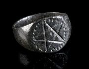 A MEDIEVAL BRONZE RING WITH A PENTAGRAM Circa 10th-13th century AD. Ring with oval bezel depicting a pentagram framed by a beaded border. Ring size 46...