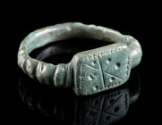 A LATE ROMAN BRONZE RING WITH A STAR DESIGN Circa 4th century AD. Ring with rectangular bezel featuring an engraved star and punched dots. Possibly an...