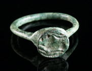 A LATE ANTIQUE/EARLY BYZANTINE BRONZE RING WITH AN ANTELOPE Circa 5th-7th century AD. Ring with projecting round bezel depicting a resting antelope se...