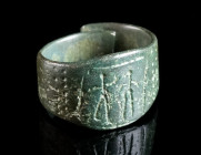 A MEDIEVAL BRONZE RING WITH TWO FIGURES Circa 10th-13th century AD. Hoop with overlapping ends; the bezel incised/punched with two standing figures wi...