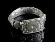 A MEDIEVAL BRONZE RING WITH ORNAMENTAL DESIGN Circa 13th-15th century AD. With an offset rectangular bezel with incised decoration and offset shoulder...