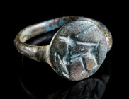 A MEDIEVAL BRONZE RING WITH A STAG Circa 12th-14th century AD. Ring with offset circular bezel depicting a stylised stag (?) prancing left. Ring size ...