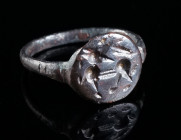 A LATE ANTIQUE BRONZE RING WITH A STYLISED ANIMAL Circa 4th-6th century AD. Ring with offset circular bezel depicting a highly abstracted animal stand...