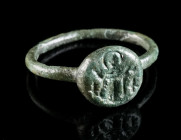 AN EARLY BYZANTINE BRONZE RING WITH A SAINT Circa 6th-7th century AD. Ring with offset round bezel depicting a facing saint with halo, his hands uprai...