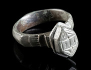 A LATE MEDIEVAL OR EARLY MODERN BRONZE RING Circa 15th-16th century AD. Ring with projecting hexagonal, decorated bezel and offset shoulders. Ring siz...