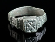 A MEDIEVAL BRONZE RING WITH SQUARE BEZEL Circa 13th-15th century AD. Ring with projecting square bezel with incised decoration. The hoop with several ...