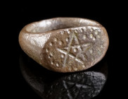 A SMALL MEDIEVAL BRONZE RING WITH A PENTAGRAM Circa 10th-13th century AD. Ring with oval bezel depicting a pentagram framed by a beaded border. Outer ...