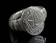 A LATE MEDIEVAL OR EARLY MODERN BRONZE RING Circa 15th-16th century AD. Ring with an oval bezel and offset shoulders, decorated with an incised design...