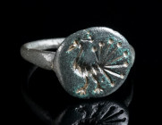 AN EARLY BYZANTINE BRONZE RING WITH A PEACOCK Circa 6th-7th century AD. With an offset circular bezel engraved with a stylised peacock striding left. ...