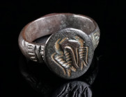 A LATE BYZANTINE BRONZE RING WITH TWO EAGLES Circa 12th-14th century AD. With an oval bezel decorated with two engraved eagles (?), and an incised sma...