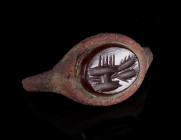 A BEZEL OF A ROMAN BRONZE RING WITH A CARNELIAN INTAGLIO Circa 2nd-3rd century AD. The intaglio features two ears of corn and possibly highly stylised...