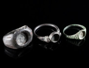 A GROUP OF THREE BRONZE/SILVER RINGS Circa 3rd-8th century AD. A heavy Roman third century ring, a silver ring, and a bronze ring; all with setting fo...