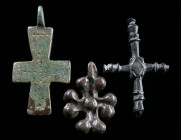 A GROUP OF THREE BYZANTINE BRONZE CROSS PENDANTS Circa 6th-12th century AD. Three small decorated cross pendants. Suspension loop of one piece broken....