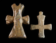 TWO BYZANTINE LEAD CROSS PENDANTS Circa 6th-11th century AD. A solid and very heavy cross pendant (?) with a broken loop for suspension, and a small s...