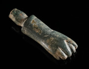 A ROMAN BRONZE MANUS FICA AMULET Circa 2nd-3rd century AD. A heavy bronze amulet in the shape of a fist with the thumb wedged in between two fingers. ...