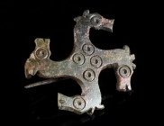 A ROMAN BRONZE SWASTIKA BROOCH WITH HORSE HEADS Circa 2nd-3rd century AD. The eyes indicated with ring-and-dot, further ring-and-dot motifs on the bod...