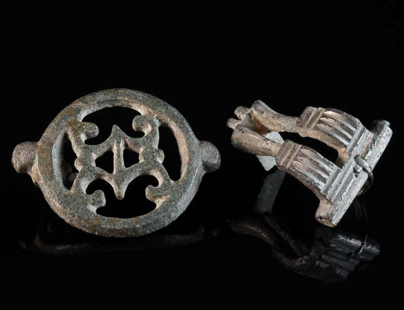 TWO ROMAN BRONZE BROOCHES Circa 2nd-3rd century AD. An openwork disk brooch with...