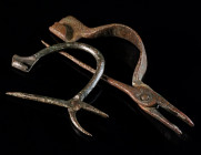 TWO ROMAN BRONZE PINCER BROOCHES Circa 2nd-3rd century AD. Both with rounded bow with two mouth-like openings, hinged together by a rivet. The larger ...