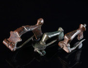 A GROUP OF THREE ROMAN BRONZE BROOCHES Circa 2nd-3rd century AD. Two knee brooches, and a bow brooch; two with hinged pin, one with spring and pin. L ...