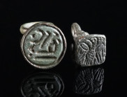 A BYZANTINE AND AN EARLY ISLAMIC BRONZE STAMP SEAL Circa 8th-10th century AD, and 14th-15th century AD. A Byzantine seal matrix with suspension loop d...