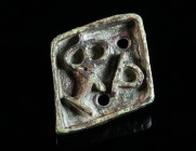 A BYZANTINE BRONZE BREAD STAMP Circa 5th-8th century AD. Rhomboid in form, with an abbreviated Greek inscription and a small strap loop/handle at the ...