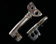 TWO BYZANTINE BRONZE KEYS Circa 5th-7th century AD. Both with pierced head, the larger key with a long, hollow shank, the smaller with a short, hollow...