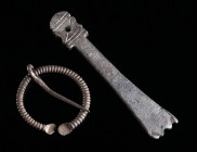 A ROMAN SILVER PENANNULAR BROOCH AND A STRAP-END Circa 1st-3rd century AD. A small Penannular/Omega brooch with a ribbed frame, and a strap-end decora...