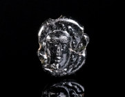 A FLAT ROMAN GLASS BEAD WITH MEDUSA Circa 3rd-4th century AD. Opaque dark glass (black in appearance) spacer bead with a head of Medusa in relief; mou...